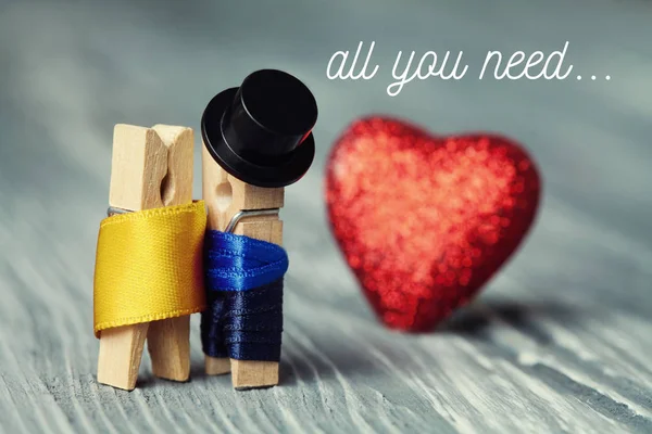 All you need is love invitation card. Romantic clothespin characters. Gentleman in black hat and woman in gold dress, red heart background. Creative design retro style postcard. Macro view