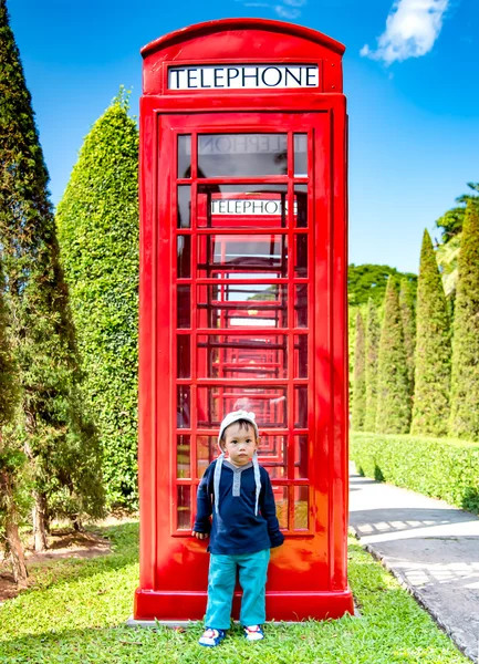 Portrait of Asian baby boy stand beside of red phone booth