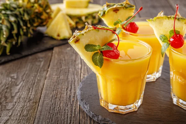 Glasses of pineapple juice with pieces of pineapple, cocktail ch