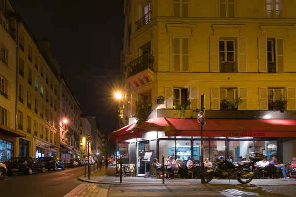 Paris by night. The people sit and talk in a cafe.