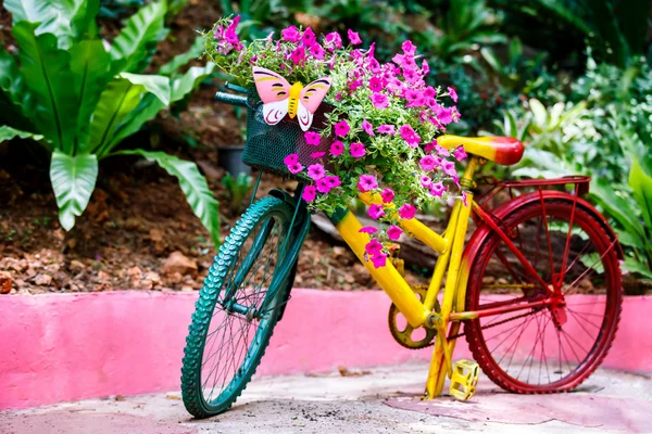 Colorful painted bicycle decorated with flowers and butterfly outdoors at green tropical garden background.