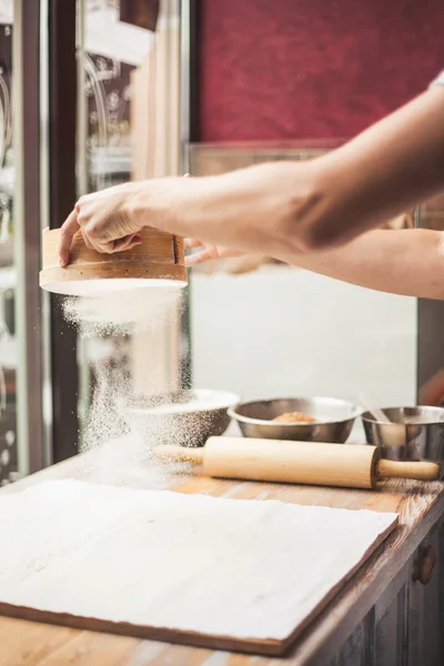Man hands spilling powder on dough.