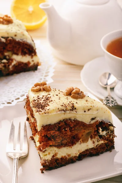 Piece of carrot cake with cheese cream on white background.