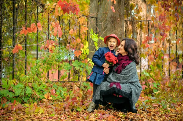 Mother with a surprised face fooling around with a daughter in autumn