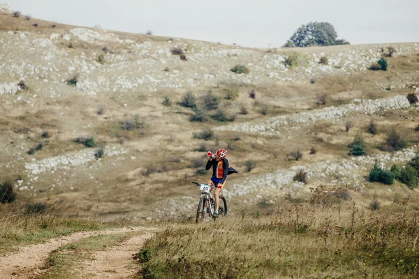 Racer cyclist on mountain bike drinking water from a bottle