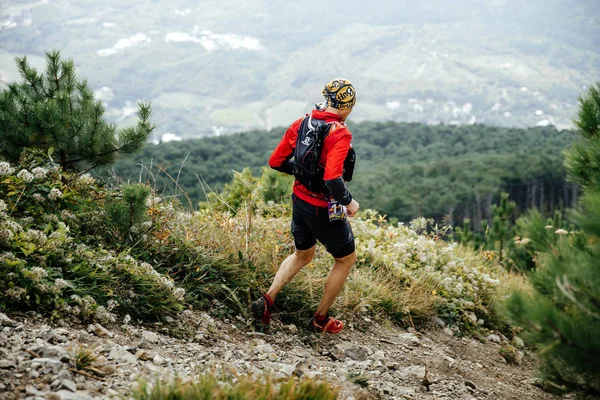 Male athlete marathon runner running with mountains along trail