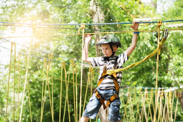 Kids climbing in adventure park. Boy enjoys climbing in the rope
