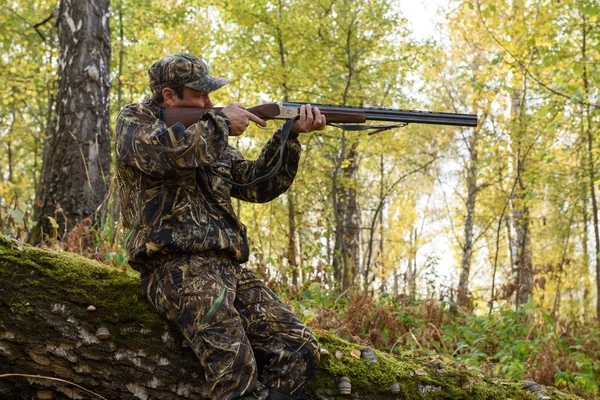 Hunter with a gun in the autumn woods