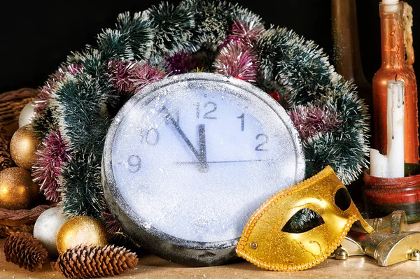 Christmas still life , clock and fir branches, carnival mask covered with snow