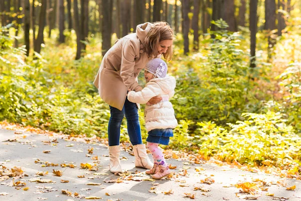 Mother and daughter playing together in the autumn park