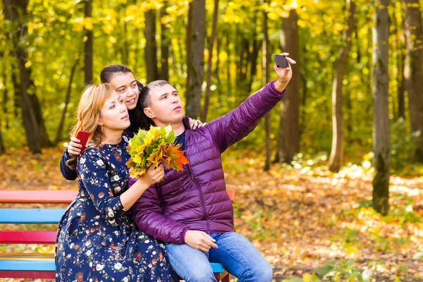 Family, childhood, season, technology and people concept - happy family photographing in autumn park