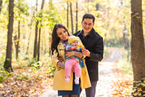 Love, parenthood, family, season and people concept - smiling couple with baby in autumn park