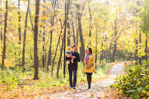 Love, parenthood, family, season and people concept - smiling couple with baby in autumn park