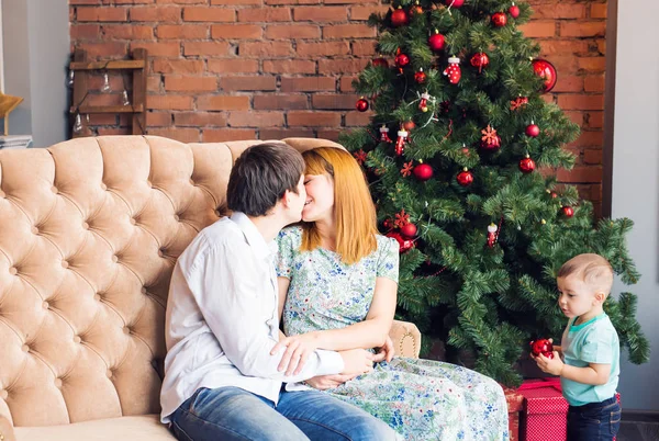 Winter, couple, christmas and people concept - man and woman kissing over x-mas tree background and child