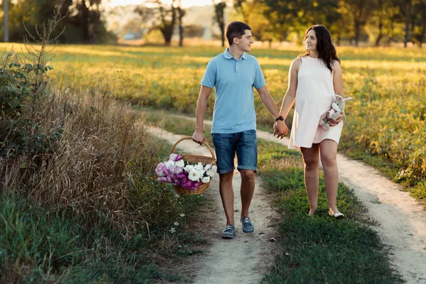 Man and pregnant woman walking in meadow