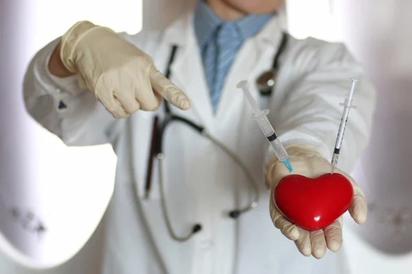 Syringe in heart doctor hand