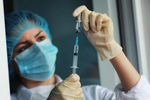 Nurse hands holding syringe and ampoule