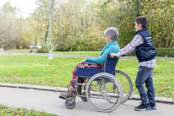 Grandson is pushing his grandmother in a wheelchair