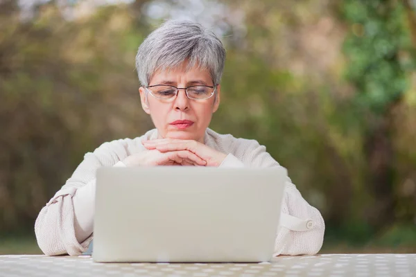 Older woman in a park using laptop computer
