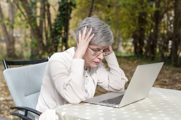 Worried woman in a park using laptop computer