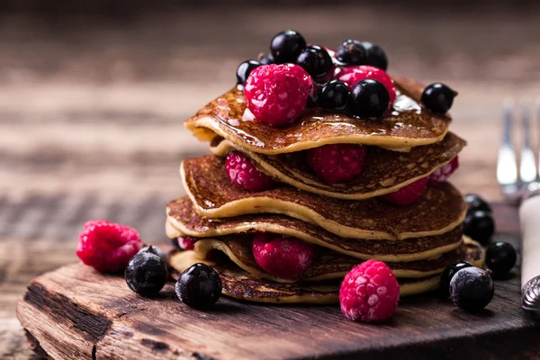 Buckwheat pancakes with berry fruit and honey on wooden vintage table