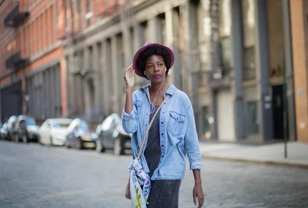Fashionable African American woman walking and listening to musi