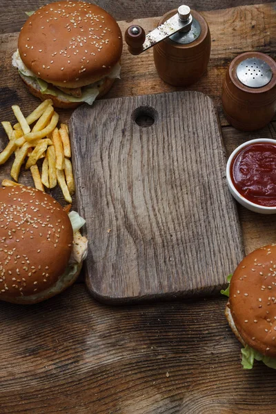 Food party table concept. Grill Sausage Sandwiches with two hamburger , potatoes fried and various sauce served on rustic table from above.