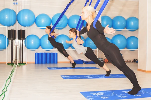 Young women doing aerial yoga exercise or antigravity yoga