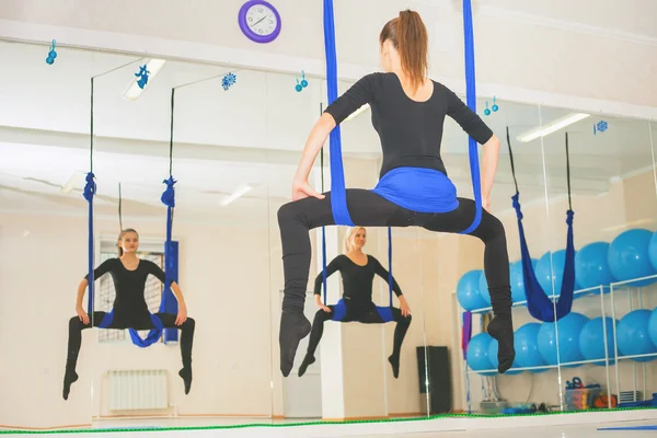 Young women doing aerial yoga exercise or antigravity yoga