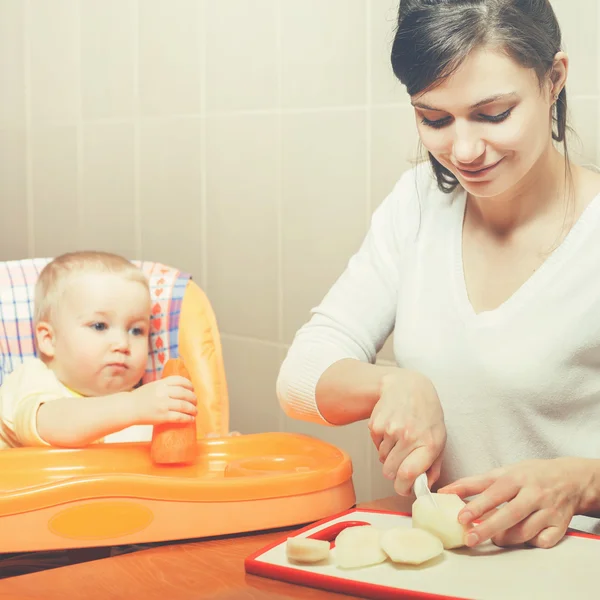 Mom cooking and feeds the baby fruits and vegetables