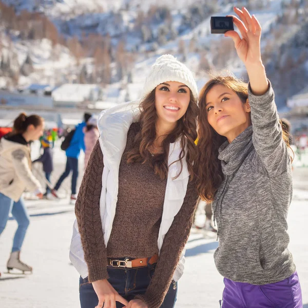Image of funny teenagers girls taking selfie, ice rink outdoor