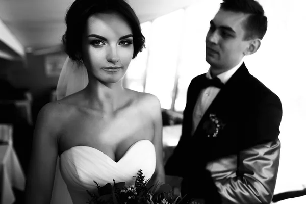 Bride looks serious while fiance stands on the background