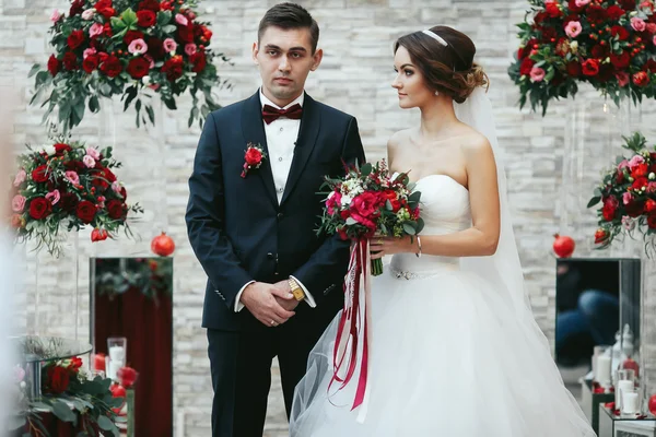 Bride look dreamy at the fiance among the red bouquets