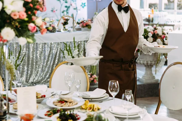 Wedding waiter is serving a table