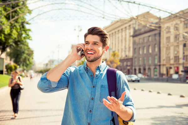 Portrait of young excited happy man talking with friend on phone