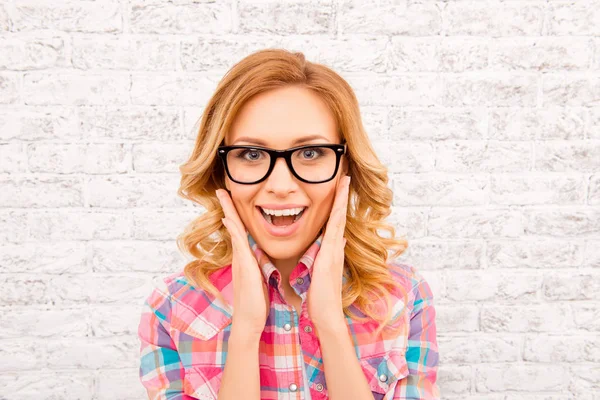 Portrait of surprised blonde in glasses touching her face