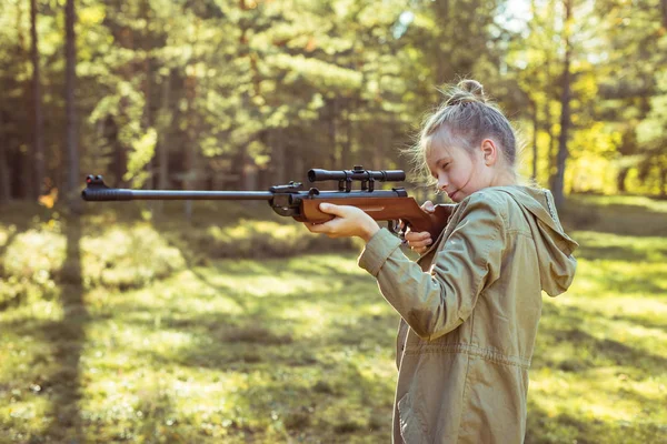 Girl shooting from the air rifle in the forest