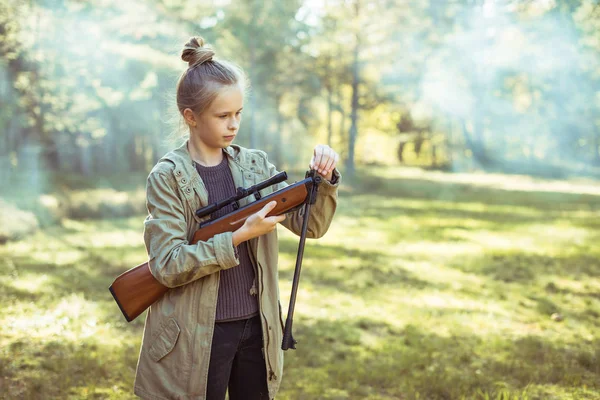 Girl shooting from the air rifle in the forest