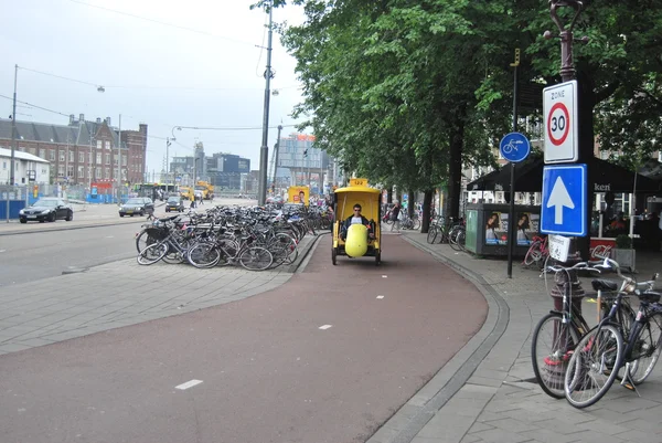 Amsterdam, Netherlands - Yellow bike taxi in the cycle lane in a cloudy day