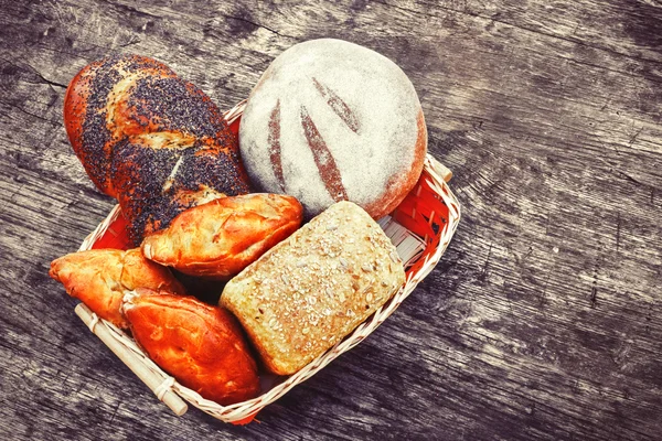 Bakery bread and rolls on old wooden table in wicker basket. The concept of food advertising. Lots of fresh bakery products. Vintage composition.