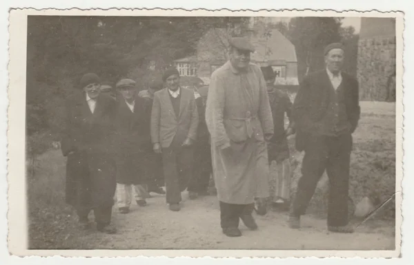 Vintage photo shows a group of men goes for a walk. Retro black & white  photography.