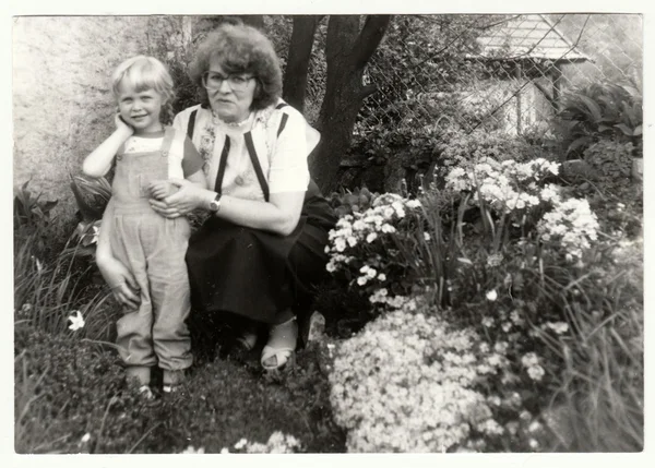 Vintage photo shows woman with a small girl in the garden. Holidays in the summertime. Retro black & white  photography
