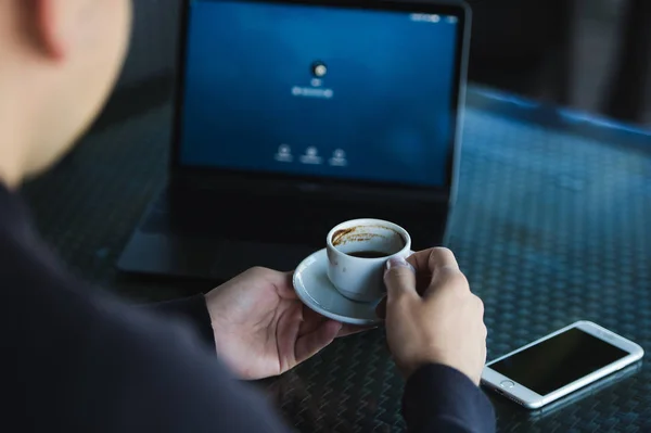 Fresh coffee for great ideas. Top view man working on laptop and holding cup of coffe while sitting at cafe