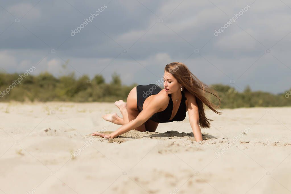 Обнаженная худышка стоит на коленях на светлом песке