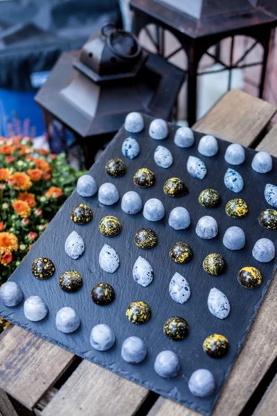 Chocolate hand made candy bonbons on a black slate plate as part of candy bar sweet table. Autumn decoration. Natural light