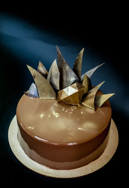 Trendy modern chocolate mousse cake decorated with mirror glaze and chocolate decor. Black background.