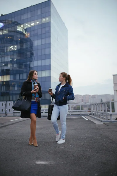 Two joyful women friends walking in city and speaking