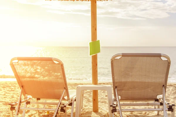 Gray straw umbrella on beautiful beach and ocean with burning sun