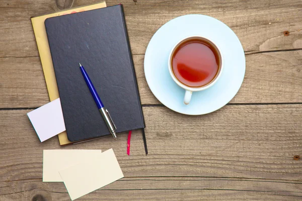Blank business cards with pen, notebook and tea cup on wooden office table