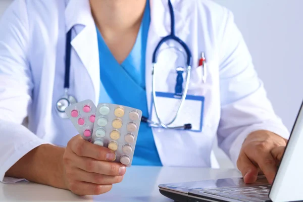 Male medicine doctor hands hold jar of pills and type something on laptop computer keyboard. Panacea life save, prescribing treatment, legal drug store, take stock, consumption statistics concept